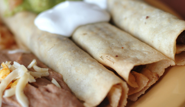 Three flute-shaped tacos filled with chicken and cheese, served with rice, beans
